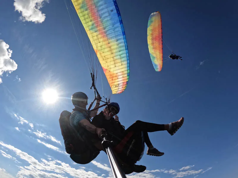 Guest waving during a tandem flight high above the Chiemgau